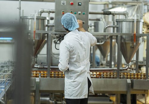 Inspector monitoring canned food production line in an industrial facility Focus on quality control automation and workflow efficiency in food manufacturing.